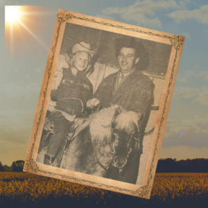 Photo of young girl on a pony with her dad standing next to the pony